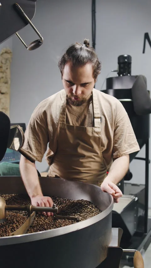 Coffee roaster carefully monitors beans in a roasting machine at a local coffee Stock Footage 321765884