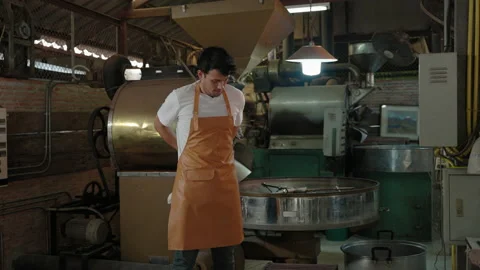 Coffee roaster is putting on an apron and gloves to start roasting work Stock Footage 202212981