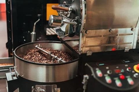 Coffee roasting machine processing beans inside metal drum, rotating and he.. Stock Photos