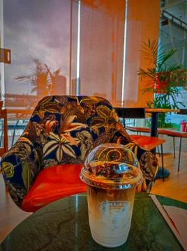 Coffee served in a stylish cup on a table beside a green plant in a cafe wi.. Stock Photos