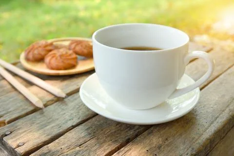 Coffee is served in a white cup, placed on a wooden table with a cookie. It i Stock Photos