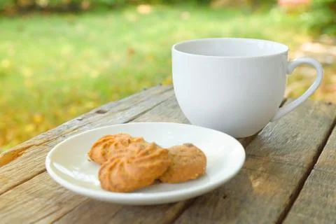 Coffee is served in a white cup, placed on a wooden table with a cookie. It i Foto stock