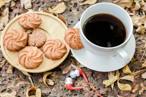 Coffee is served in a white cup, placed on a wooden table with a cookie. It i Stock Photos
