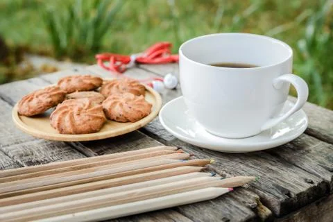 Coffee is served in a white cup, placed on a wooden table with a cookie. It i Stock Photos