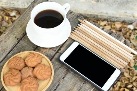 Coffee is served in a white cup, placed on a wooden table with a cookie. It i Stock Photos