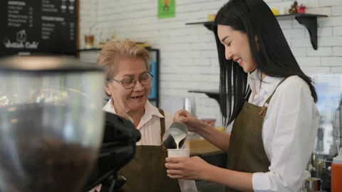 Coffee shop concept of 4k Resolution. An old woman teaching a young female em Stock Footage 208562470