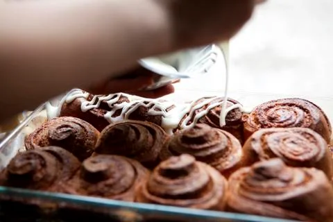 A coffee shop employee frosting cinnamon rolls with icing Stock Photos
