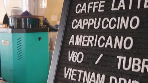 Coffee shop menu board displaying various menus next to a coffee grinder. Video stock 343407069