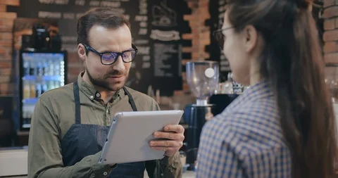 Coffee shop owner using tablet pc to take customer order Stock Footage