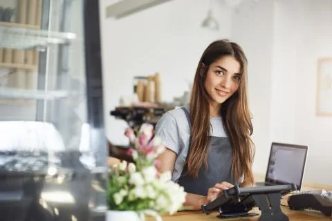 Coffee shop owner using a tablet looking at camera smiling, ready for her first Stock Photos