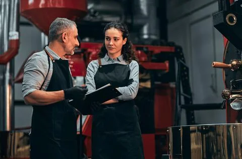 Coffee shop workers checking coffee beans roasting process together and make  Stock Photos