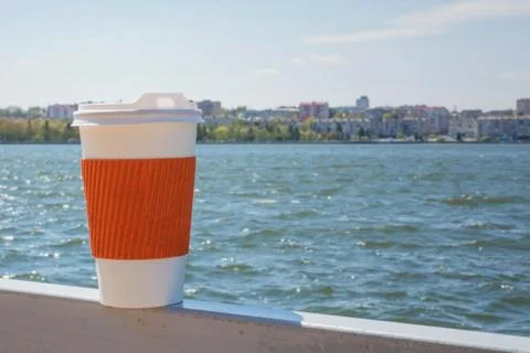 Coffee single cup on the background of the lake and the city in bokeh. Stock Photos