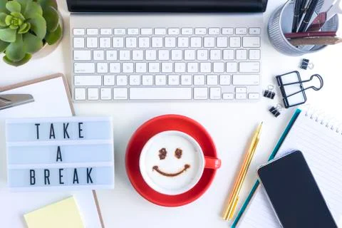 Coffee with smiley on top with computer and smartphone on office table Stock Photos