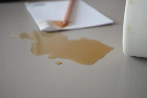 Coffee spill on table and notepad near a pencil Stock Photos