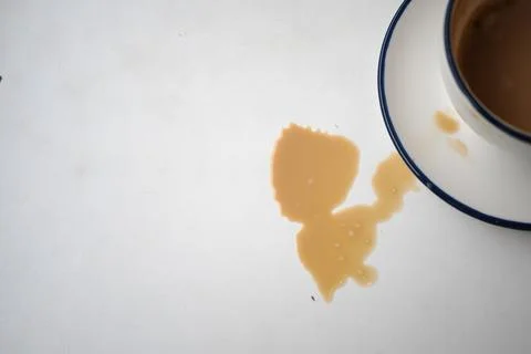 Coffee spills on a table near an empty cup Stock Photos