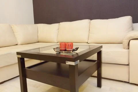 Coffee table and comfortable white corner leather sofa. Stock Photos