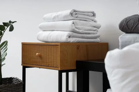 Coffee table with bed sheets near white wall in living room Stock Photos