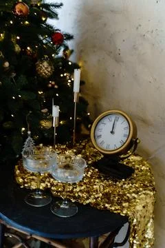 A coffee table by the Christmas tree with two glasses and a clock on it Stock Photos