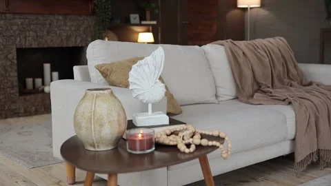 A coffee table with a stylish decor and a burning candle on a blurred background Stock Footage 233764928