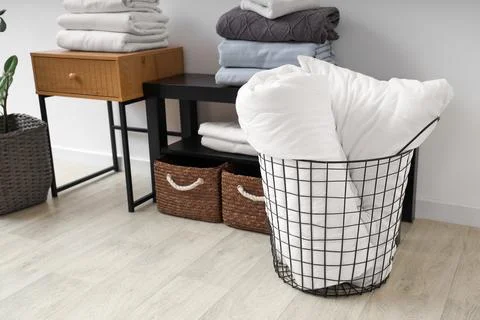 Coffee tables with baskets and bed sheets near white wall in living room Stock Photos