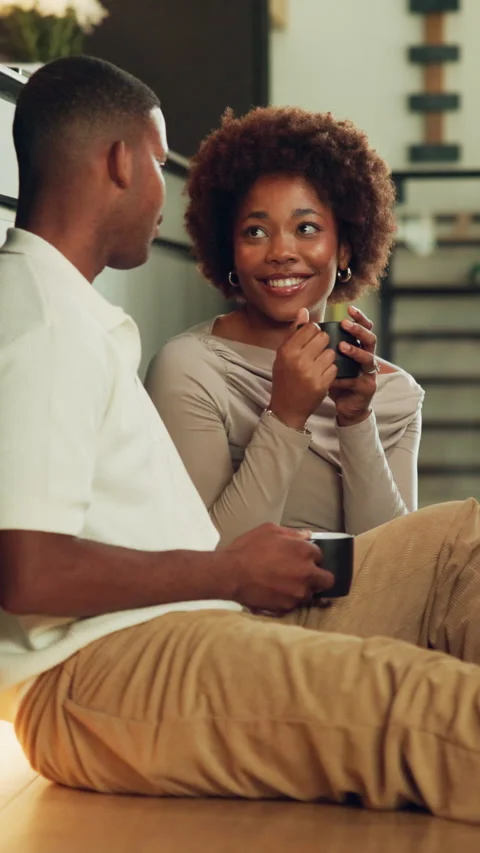 Coffee, talking and floor with black couple in kitchen for relax, bonding and Stock Footage 340774204
