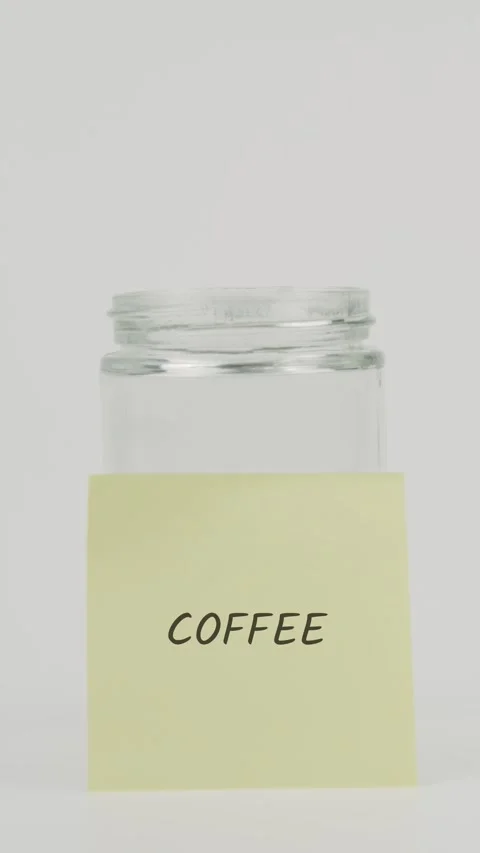 Coffee text or word on yellow sticky note attached to glass jar with hand Stock Footage 311693537