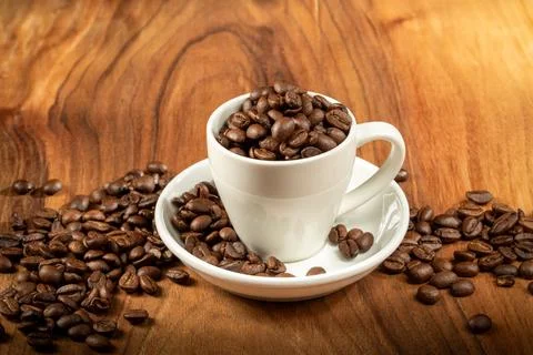 Coffee theme. A ceramic cup filled to the brim with coffee beans stands on .. Stock Photos