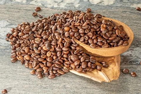 Coffee theme. Coffee beans in a cork saucer and almond leaf on the table Stock Photos