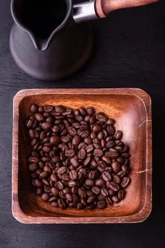 Coffee theme. Flat lay. Plate with coffee beans on black wooden table. Stock Photos