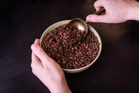 Coffee theme. Plate with coffee beans on black wooden table. Stock Photos