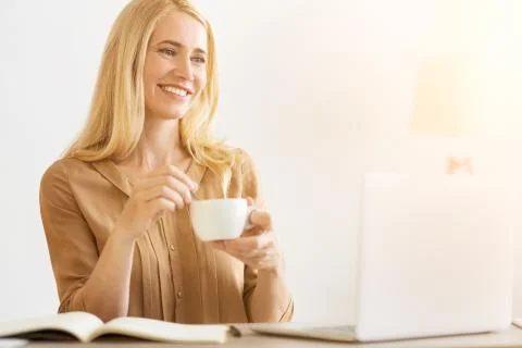 Coffee time. CEO drinking coffee and looking at laptop screen Stock Photos
