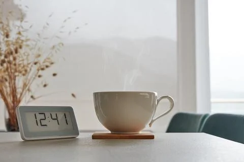 Coffee time concept. Clock with dinner time and hot mug of fresh coffee Stock Photos
