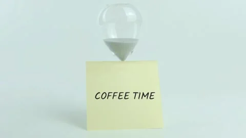 Coffee Time written on yellow sticky note placed on hourglass on white Stock Footage 313469563
