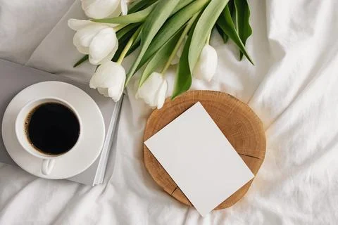 Coffee, white tulips and empty paper card on the bed Stock Photos