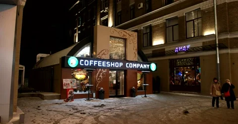 Coffeshop illuminated at night, bustle of people, city lights and buildings Stock Footage