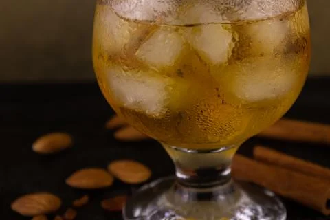 Cognac and ice in a glass with cinnamon and almonds Stock Photos