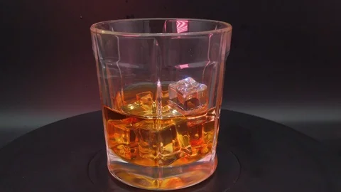 Cognac with ice cubes on a black background Stock Footage 113555070