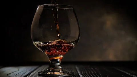 Cognac is poured into a  glass. On dark background. HD 1920x1080 Video Clip. Stock Footage 104752257