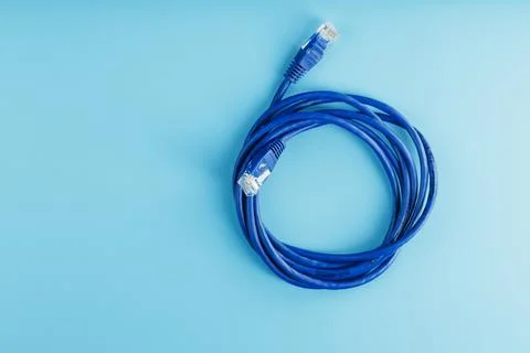 A coil of an Internet network cable for data transmission on a blue backgroun Stock Photos