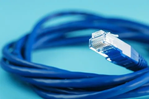 A coil of an Internet network cable for data transmission on a blue backgroun Stock Photos