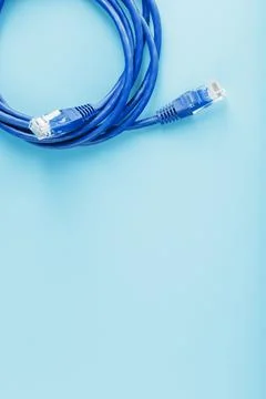 A coil of an Internet network cable for data transmission on a blue backgroun Stock Photos