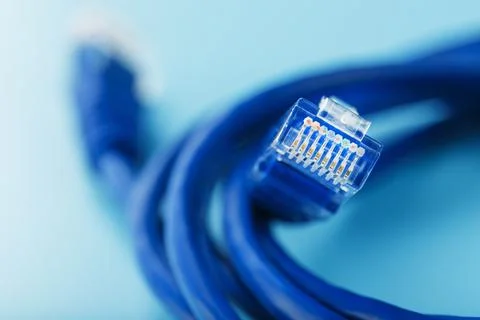A coil of an Internet network cable for data transmission on a blue backgroun Stock Photos