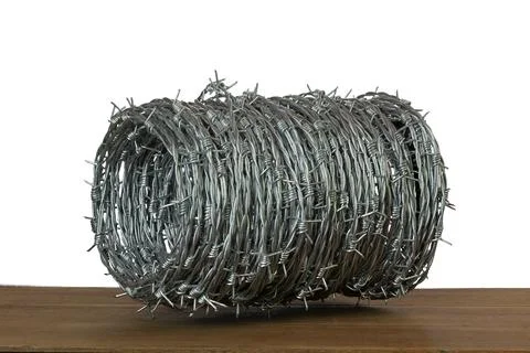 Coiled barbed wire roll isolated on wooden table against white background 스톡 사진