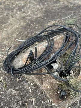 Coiled Black Electric Cable on Ground Outdoors Stock Photos