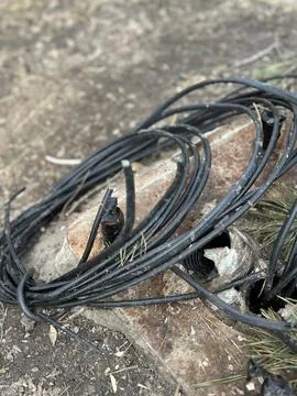 Coiled Black Electric Cable on Ground Outdoors Stock Photos