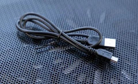 Coiled black USB data wire on textured metal background Stock Photos