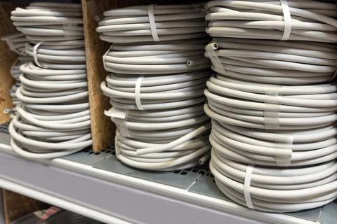 Coiled white electrical wires displayed neatly on shelves in a hardware store Stock Photos
