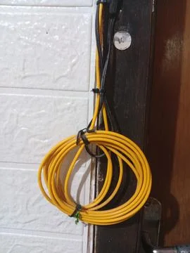 Coiled Yellow Cable Hanging on Wall Foto stock