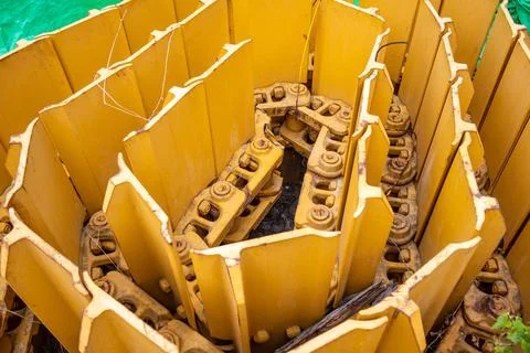 Coiled yellow continuous crawler track shoes for heavy machinery rest outdo.. Stock Photos