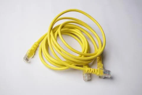 Coiled yellow Ethernet cable featuring multiple RJ45 connectors, set agains.. Stock Photos